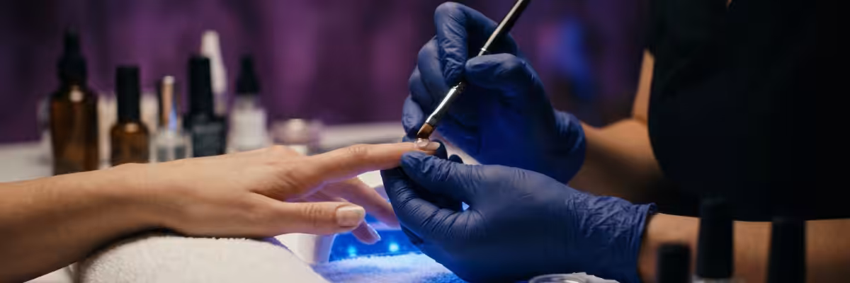 Nail designer aplicando esmalte em gel em salão profissional — entenda o que são TPO e DMPT