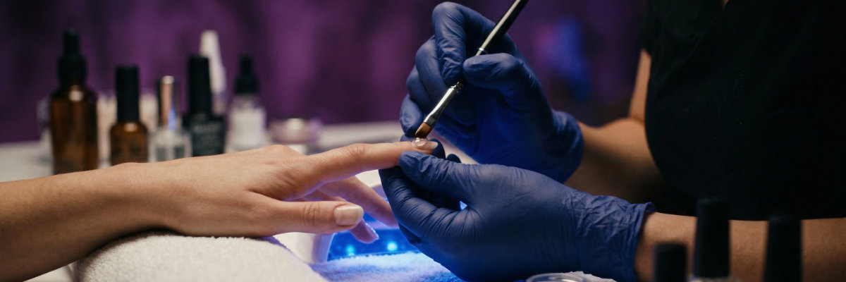 Nail designer aplicando esmalte em gel em salão profissional — entenda o que são TPO e DMPT