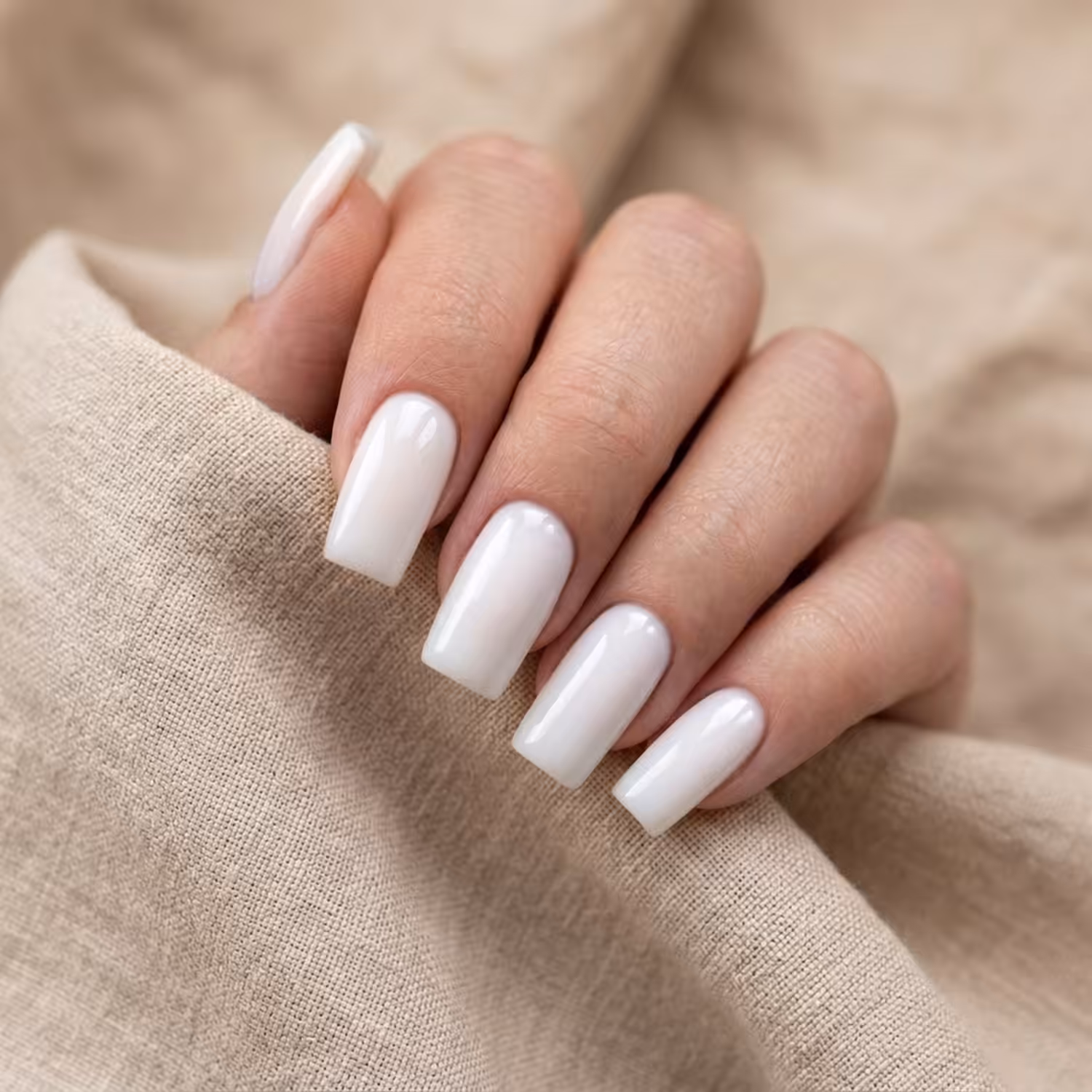 Mão com cinco unhas quadradas no Gel Construtor Branco Algodão, branco fechado, sobre linho areia