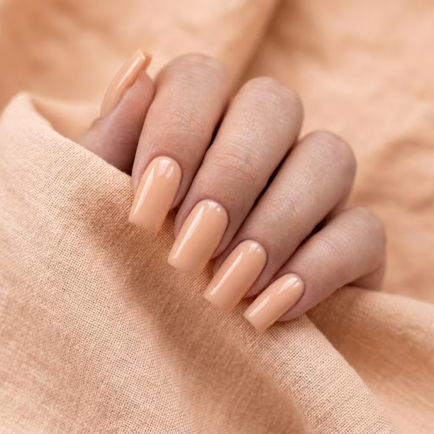 Mão com cinco unhas quadradas no Gel Construtor Velvet Cover, sobre linho pêssego