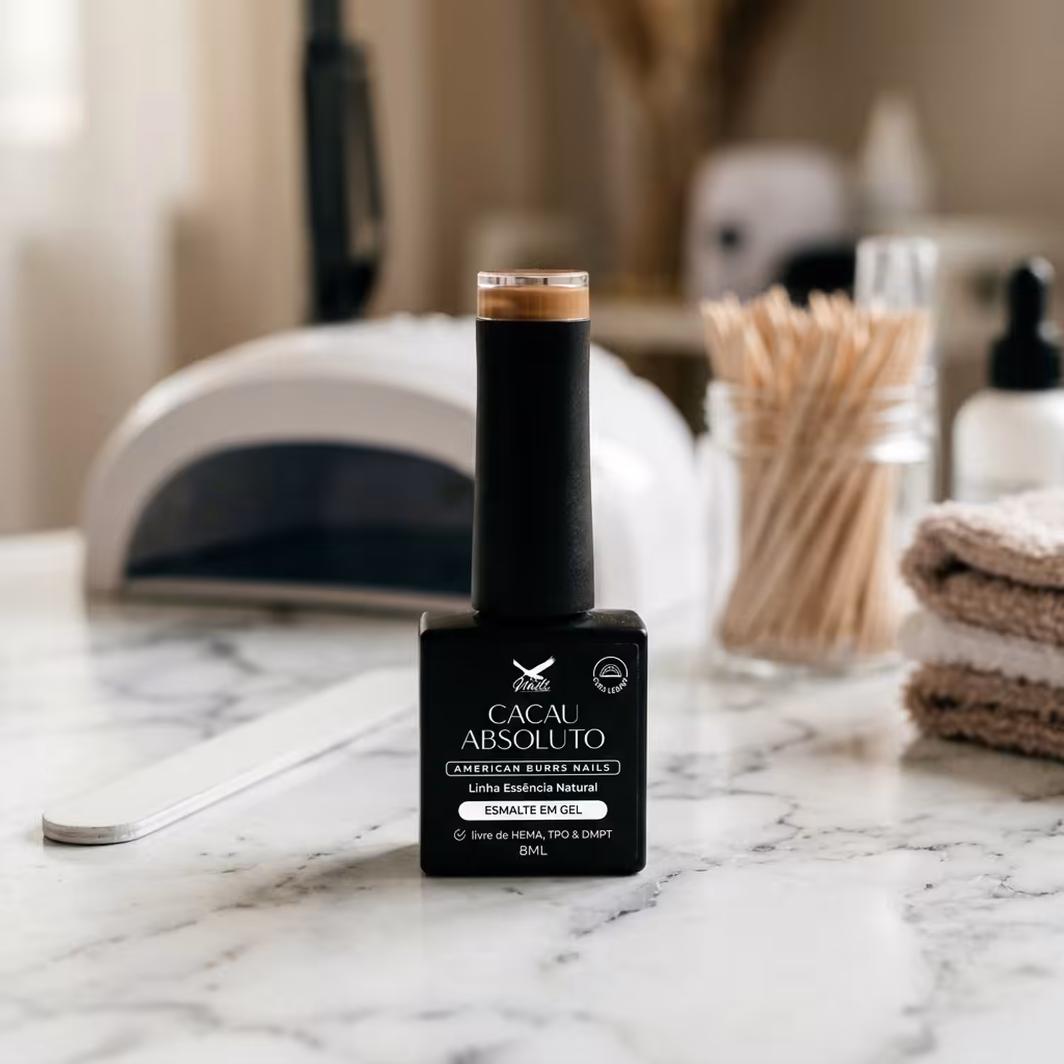 Frasco do Esmalte em Gel Cacau Absoluto, da Linha Essência Natural, sobre uma bancada de mármore