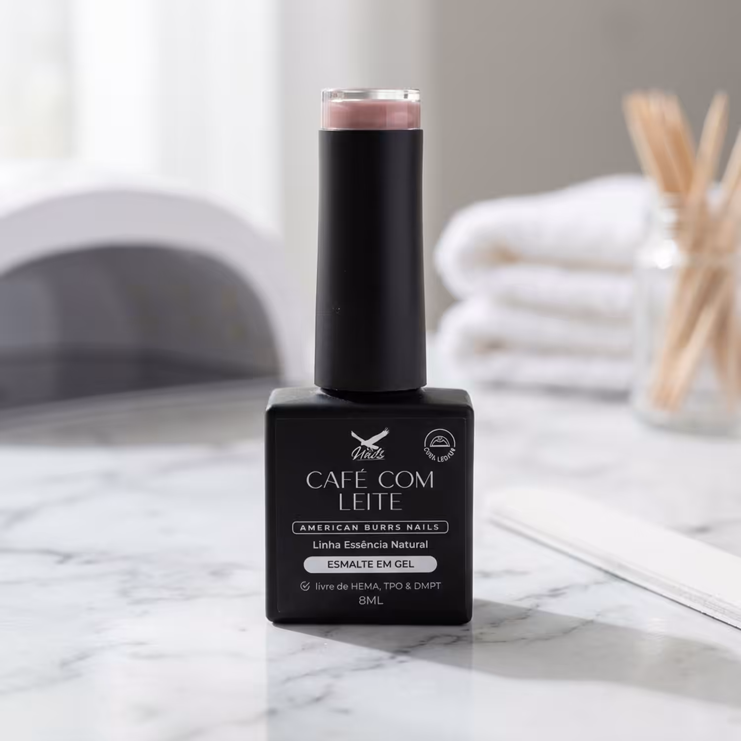 Frasco do Esmalte em Gel Café com Leite, da Linha Essência Natural, sobre uma bancada de mármore