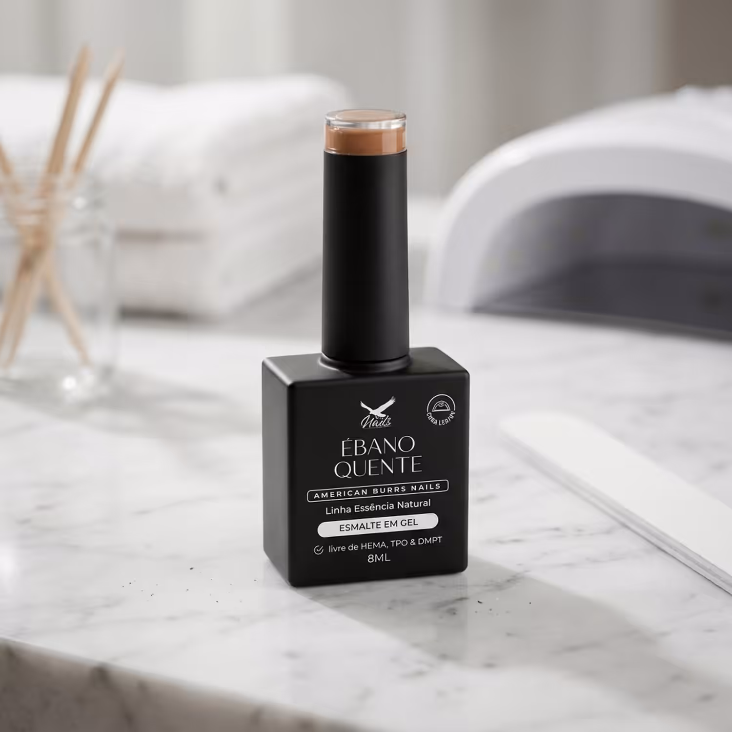 Frasco do Esmalte em Gel Ébano Quente, da Linha Essência Natural, sobre uma bancada de mármore