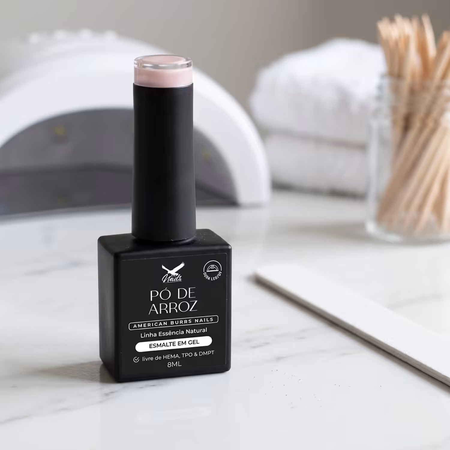 Frasco do Esmalte em Gel Pó de Arroz, da Linha Essência Natural, sobre uma bancada de mármore
