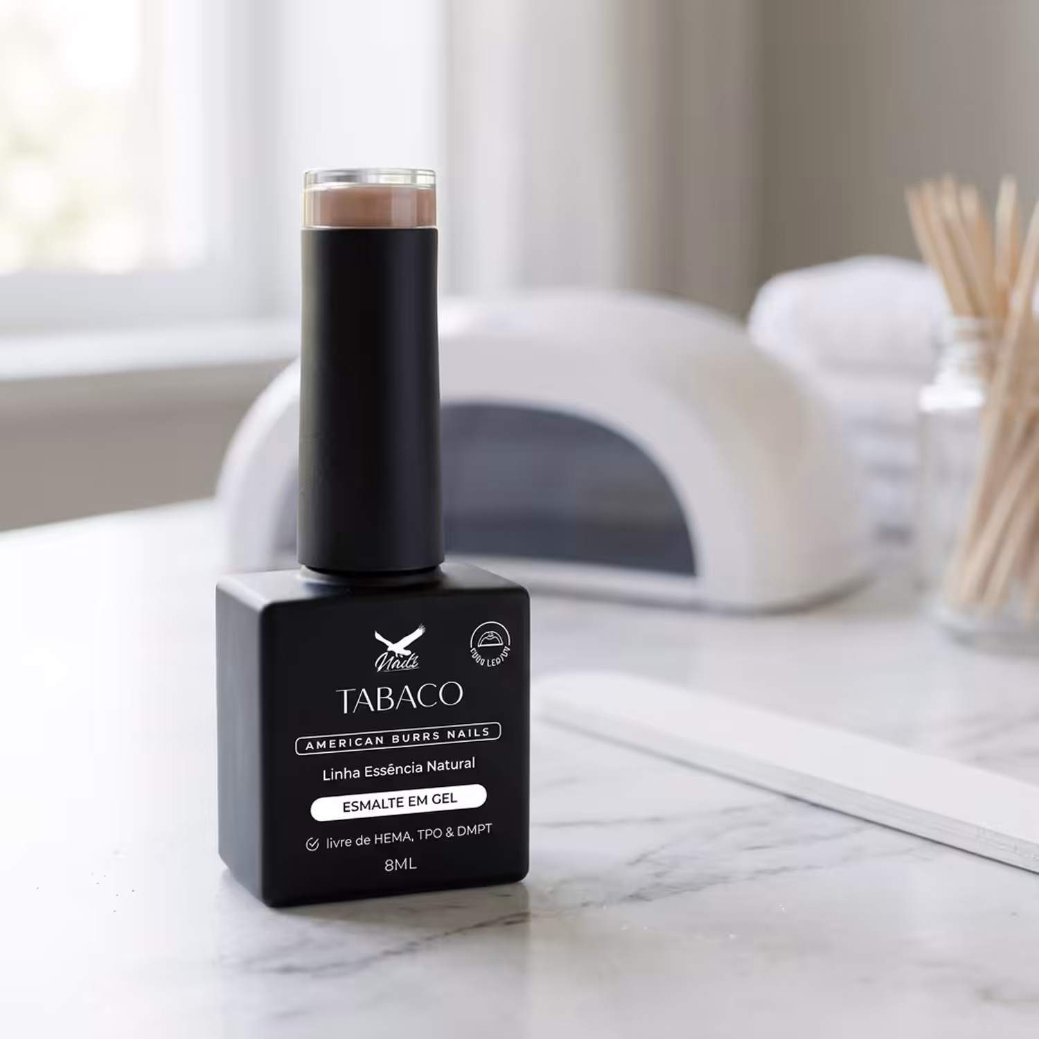 Frasco do Esmalte em Gel Tabaco, da Linha Essência Natural, sobre uma bancada de mármore
